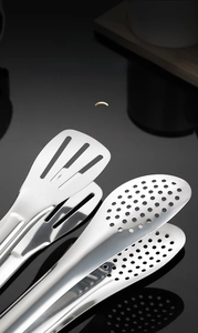 Detail of stainless steel steak tongs featuring mirror polish and uniform leak holes