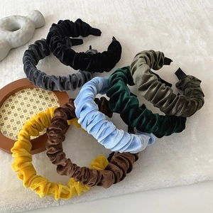 Ruched velvet headbands in multiple solid colors on a soft white decorative base