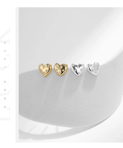 Close-up of gold and silver heart-shaped stud earrings with sparkling diamonds