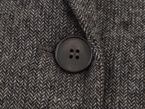 Detailed close-up of herringbone tweed fabric with premium brown resin buttons