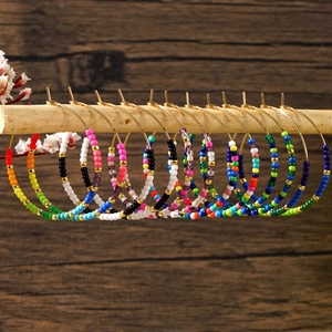 Macro detail of colorful bohemian seed bead hoop earrings on rustic wooden background