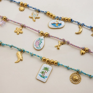 Detailed macro view of three woven charm bracelets with sun, moon and star gold pendants