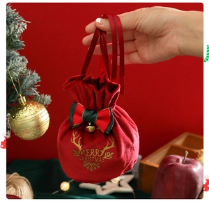Detail of red velvet Christmas drawstring gift bag with gold bells and festive bow