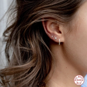 Detailed view of three-piece 925 sterling silver earring set with zircons on model ear