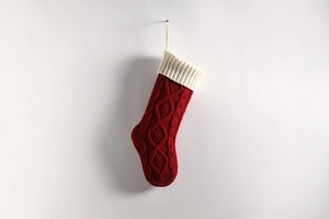 Close-up of red chunky knit Christmas stocking with white cuff and hanging loop detail