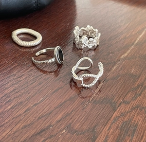 Detailed view of silver braided twist ring and vintage gemstone ring on wooden surface