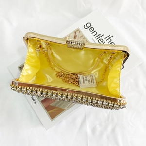 Detail of evening clutch featuring yellow satin lining, gold chain and rhinestone exterior