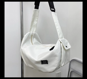 Close-up of white waterproof gym bag showing side pocket detail and wide black shoulder strap