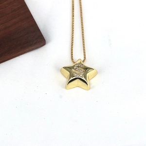Macro shot of gold star pendant with sparkling Zircon S-letter inlay on fine snake chain