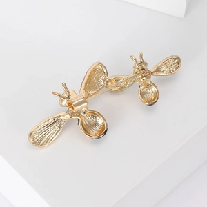 Golden alloy bee brooches with a secure safety clasp on a minimalist white background
