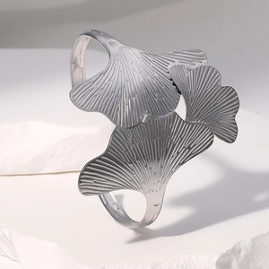 Gepolijste roestvrijstalen ginkgoblad open armband op een minimalistische witte achtergrond