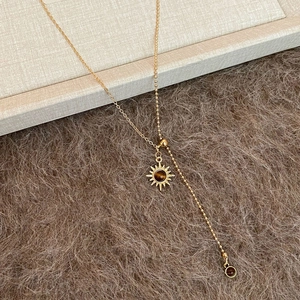 Gold tiger eye sun pendant necklace with Y-chain design on a soft plush background