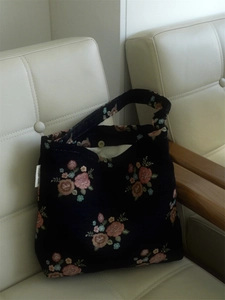 Detail of vintage floral pattern and magnetic clasp on the black fabric shoulder bag