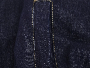 Gros plan détaillé du denim bleu foncé avec des coutures jaunes contrastées et texture