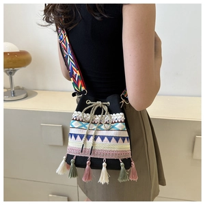 Detailed close-up of a black ethnic bucket bag with colorful woven patterns and tassels