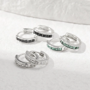 Silver hoop earrings with square emerald, black and clear stones on white stone