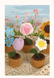 Macro detail of five handmade crochet potted flowers including roses and sunflowers