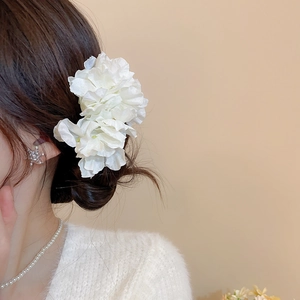 Detail view of elegant white fabric flower hair pin with smooth silk texture on a model