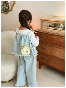 Détail du sac à bandoulière rond jaune lapin avec nœud et tenue en jean bleu
