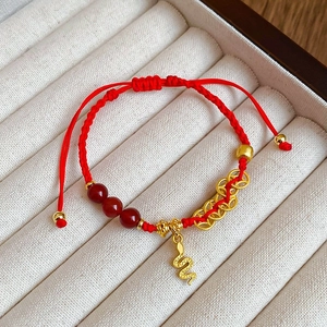 Détail du bracelet en corde tressée rouge avec pendentif serpent doré et perles