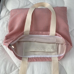 Detail of red striped canvas tote with secure zipper closure and internal phone pocket