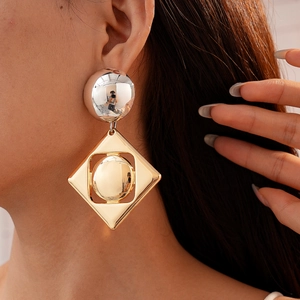 Detail of silver sphere and golden geometric diamond frame earring on a model