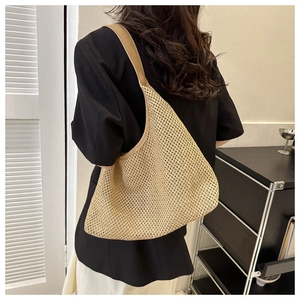 Close-up of beige woven shoulder bag texture with camel PU strap on fashion model