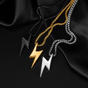 Détail de trois colliers éclair en noir, or et argent posés sur de la soie noire