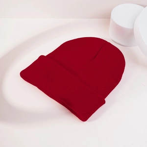 Close-up of dark red ribbed beanie with classic fold-over cuff on minimalist background