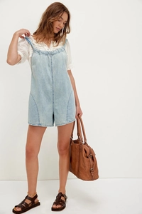 Detail view of light blue denim romper with adjustable straps and casual pockets