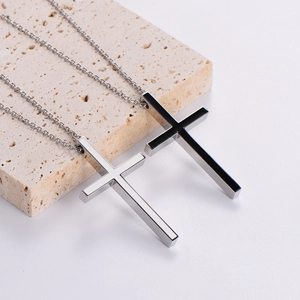 Polished silver and black stainless steel cross necklaces on a textured stone display