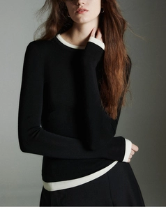 Detail of slim fit wool knit top featuring contrast white trim on black collar and cuffs