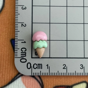 Gros plan d'un mini cornet de glace en résine de 2,2 cm, rose et vert menthe, sur tapis