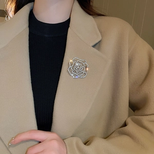 Detailed view of silver hollow rose brooch with crystals on a wool coat lapel