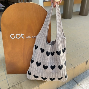 Detailed view of the thick knit texture and heart pattern on the beige tote bag