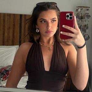Close-up of deep brown halter V-neck top styled with layered gold necklaces and earrings