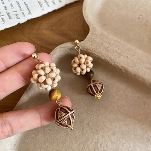 Detail of vintage tiger eye and wooden beaded pendant earrings with ethnic handcrafted texture