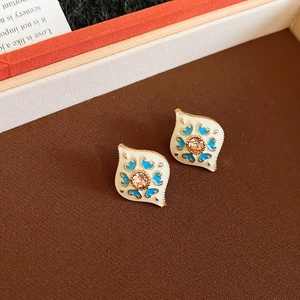 Detail of vintage enamel heart earrings with blue floral patterns and crystals
