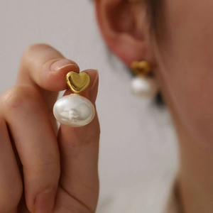 Orecchini vintage a cuore in oro 18K con perle barocche bianche indossati da una modella
