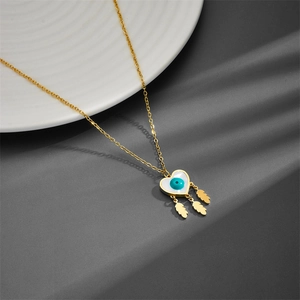 Golden heart necklace with blue evil eye pendant and leaf fringe on dark background