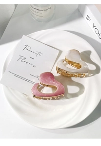 Detail of pink marble and pearl white heart-shaped hair claws on a ceramic plate