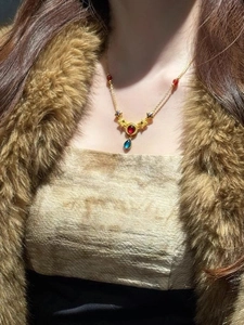 Detail view of ethnic style necklace featuring a red round stone and blue teardrop pendant