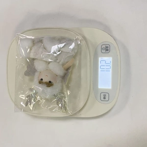 Close-up of a plush Christmas angel ornament with silver antlers on a digital scale