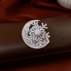 Macro shot of silver crescent moon and snowflake brooch with sparkling zircons