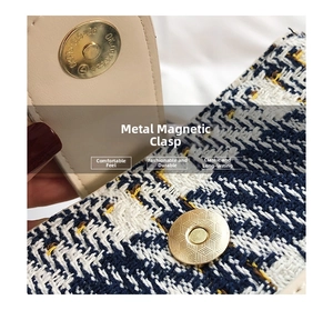 Macro shot of circular gold magnetic clasp on a blue tweed plaid textured shoulder bag