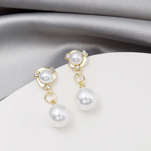Macro detail of gold double pearl drop earrings with sparkling rhinestone accents