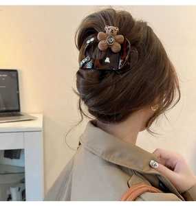 Detailed view of hair claw clip with plush brown bear and rhinestones on hair