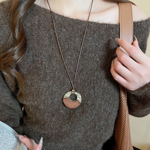 Detail of bohemian geometric round wood pendant on brown woven wax cord necklace