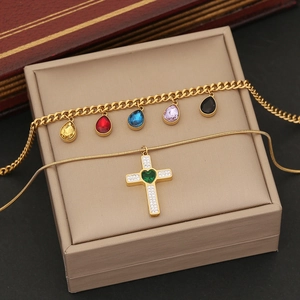 Detail of gold double layer necklace with rhinestone cross pendant and colorful charms