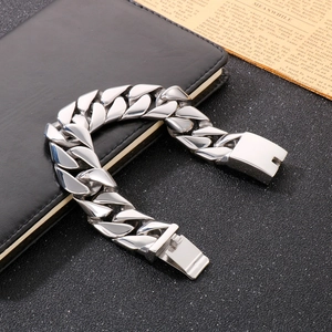 Close-up of a silver chunky Cuban link bracelet with polished finish on a black background